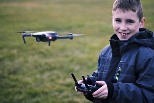 A young boy flying a drone and smiling